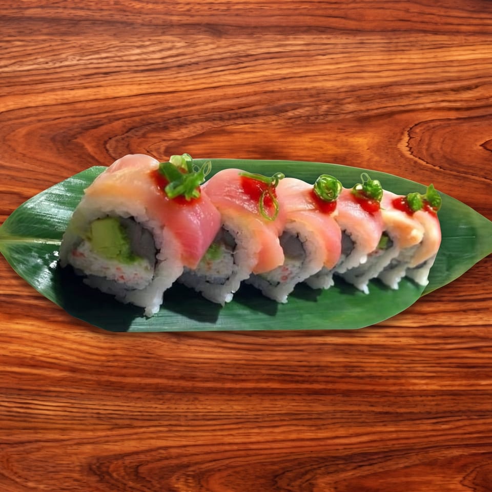 Sushi rolls with pink fish, red sauce, and green onions on a banana leaf.